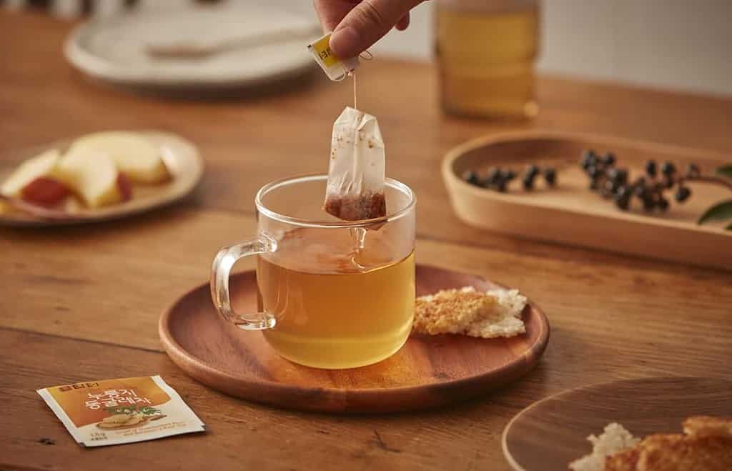 둥글레차 효능 및 부작용, 카페인, 물 대신 : 둥굴레차 1 둥글레차 티백을 물에 탄 컵에 타고 있는 사람